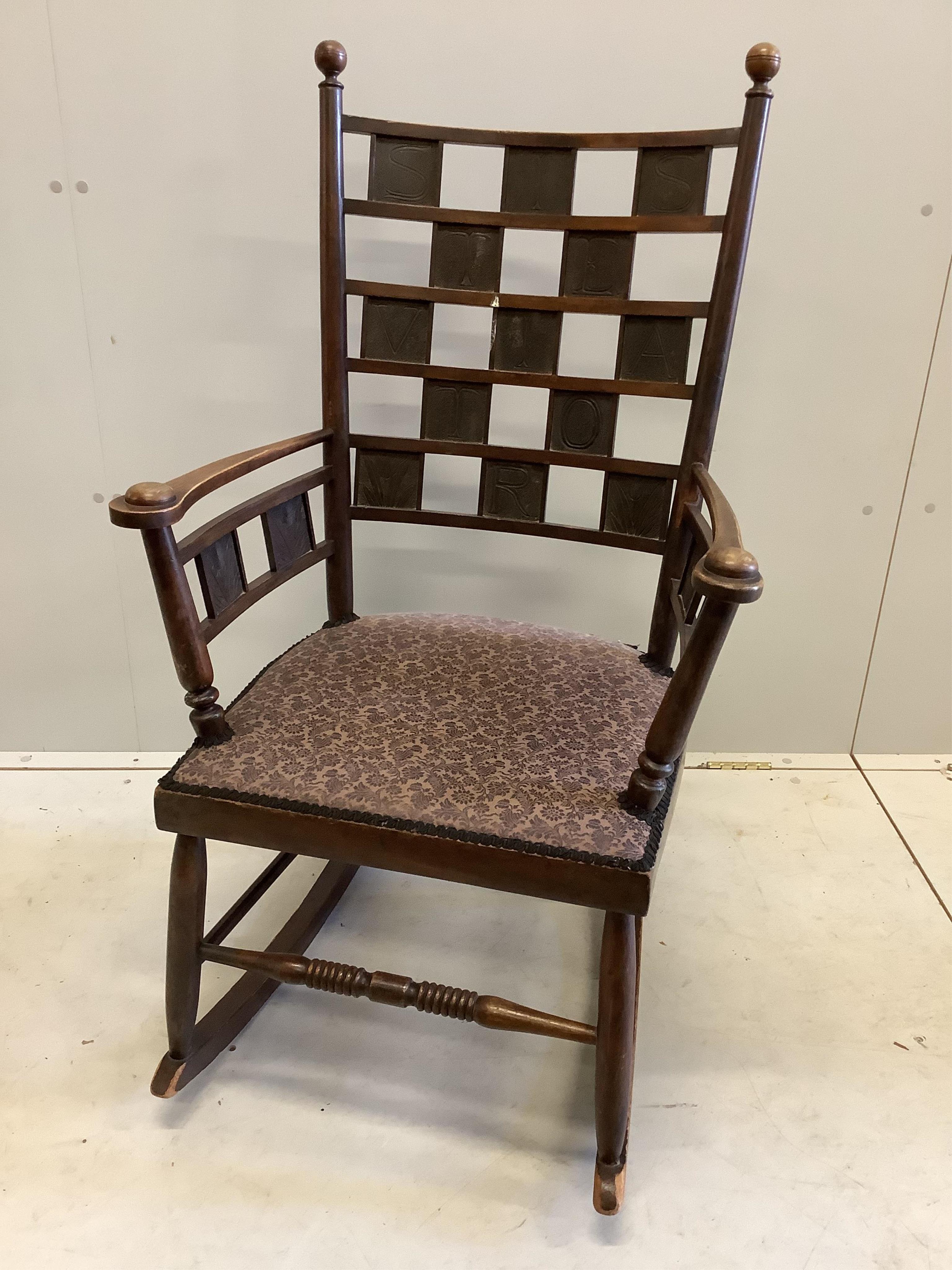 An Arts & Crafts rocking chair, the tablet back with Latin inscription, width 60cm, depth 52cm, height 108cm